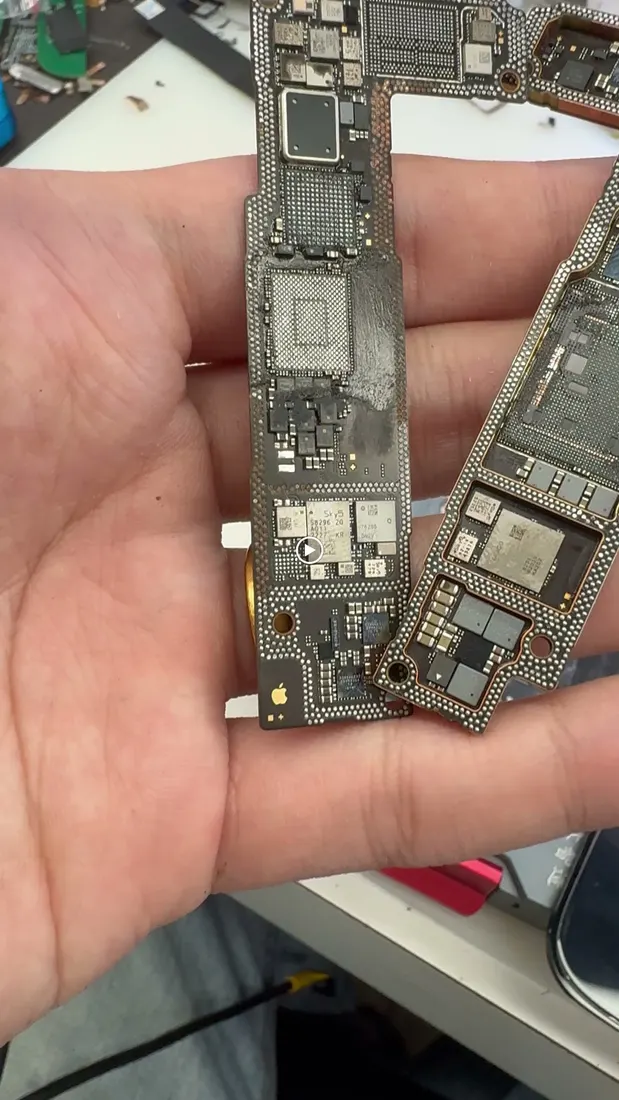 手持兩片 iPhone 14 主機板,準備進行晶片套件移植