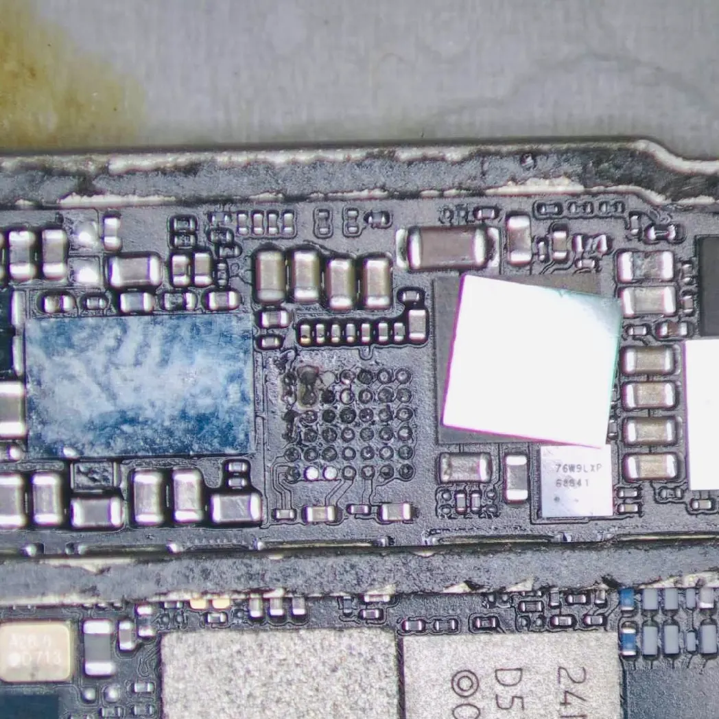 顯微鏡下的 iPhone 8 Plus 主機板，可見進水造成的藍綠色腐蝕痕跡