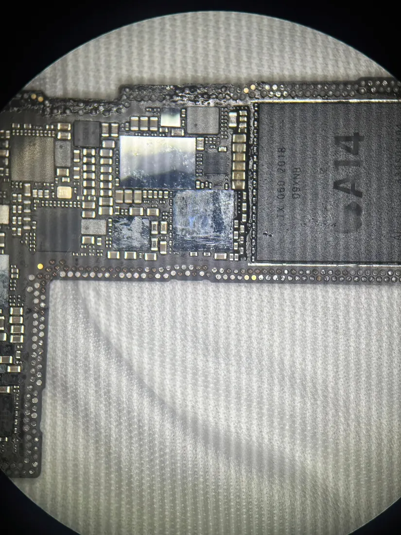 顯微鏡下的 iPhone 12 Pro 主機板，可見 A14 處理器標示