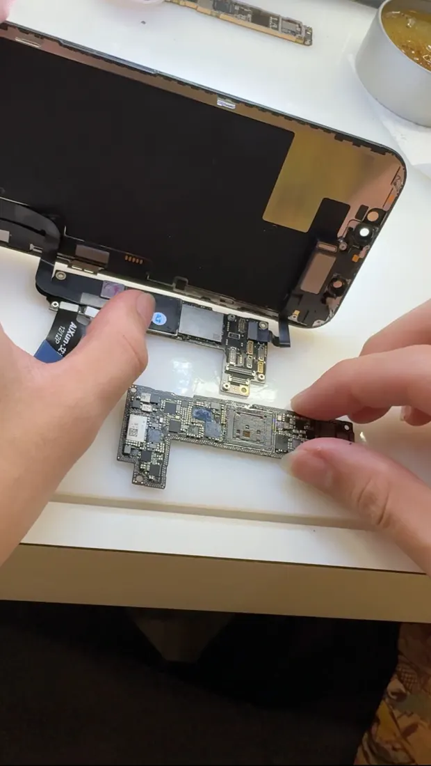 維修人員手持從摔壞的 iPhone 12 Pro 取出的主機板