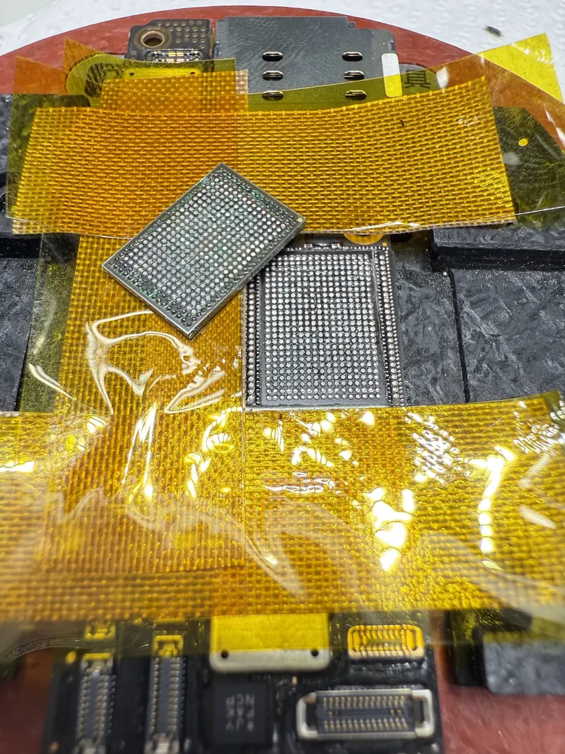 主機板以黃色高溫膠帶遮蔽，旁邊放置植錫鋼網