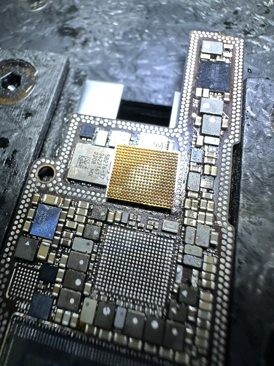 iPhone 主機板特寫，晶片位置的金色 BGA 焊盤陣列已清理完成