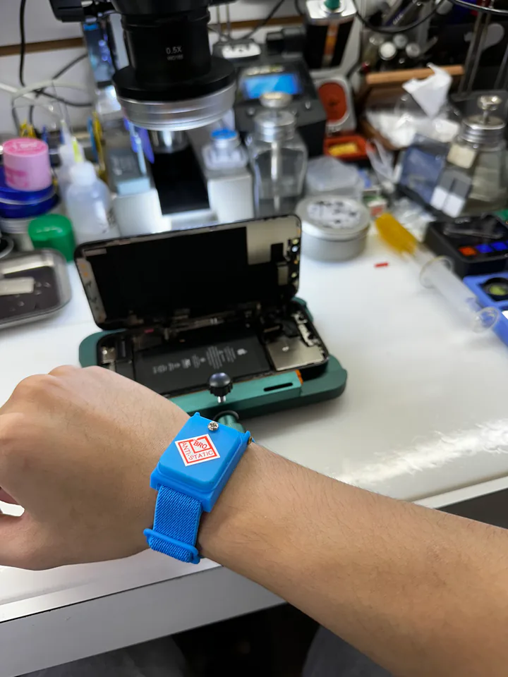 逗點技師配戴防靜電手環，在顯微鏡下處理已拆機手機